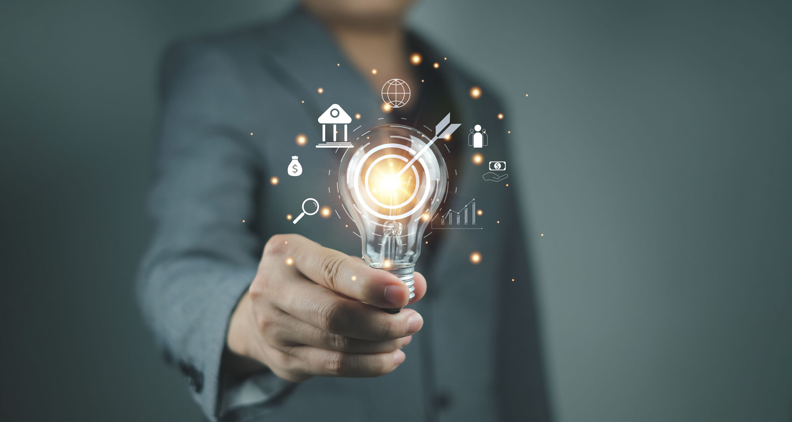 Business man holding a lightbulb with data graphics surrounding it